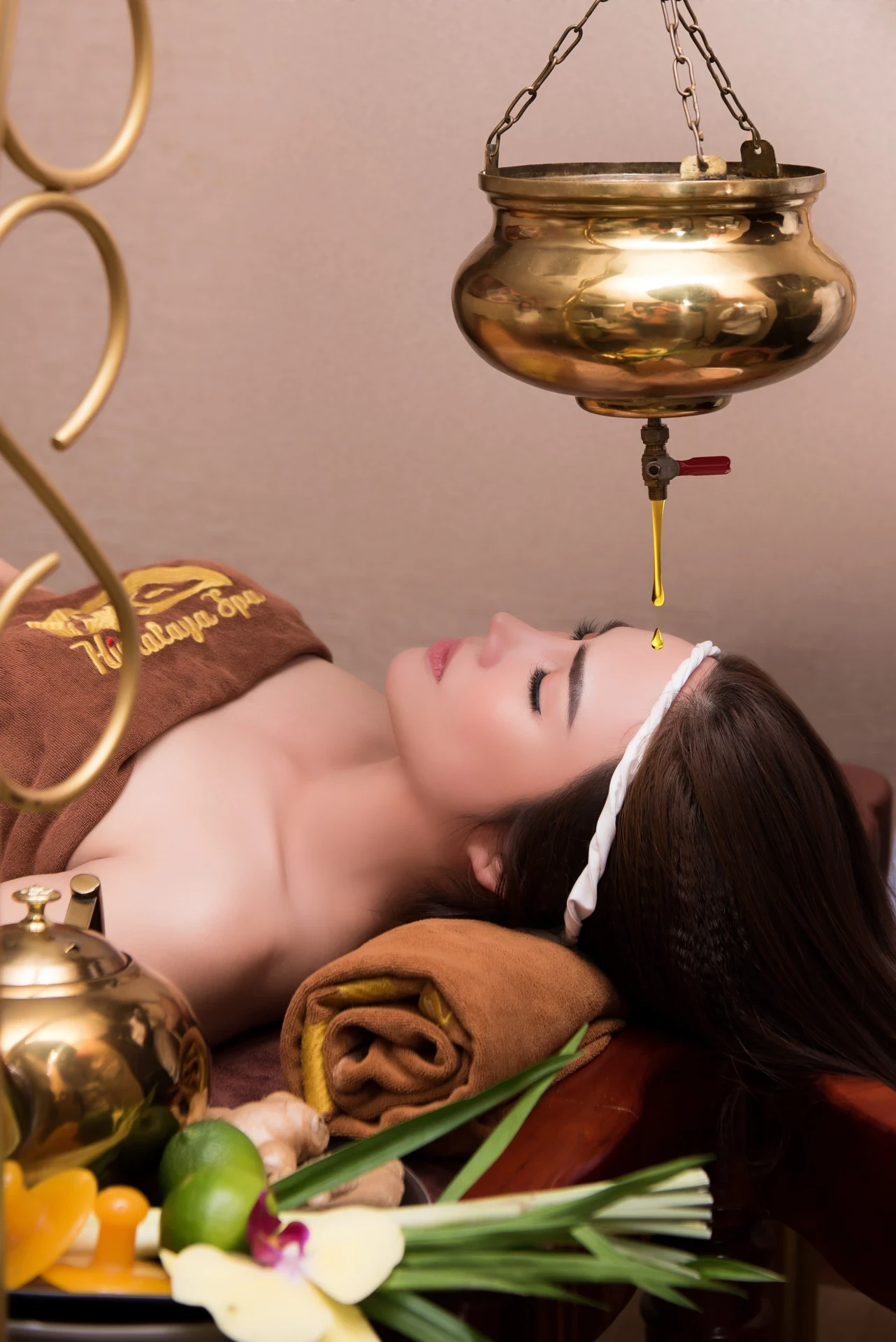 Khách nằm thư giãn với dòng dầu rót từ bình đồng xuống vùng trán theo phong cách Ayurveda
