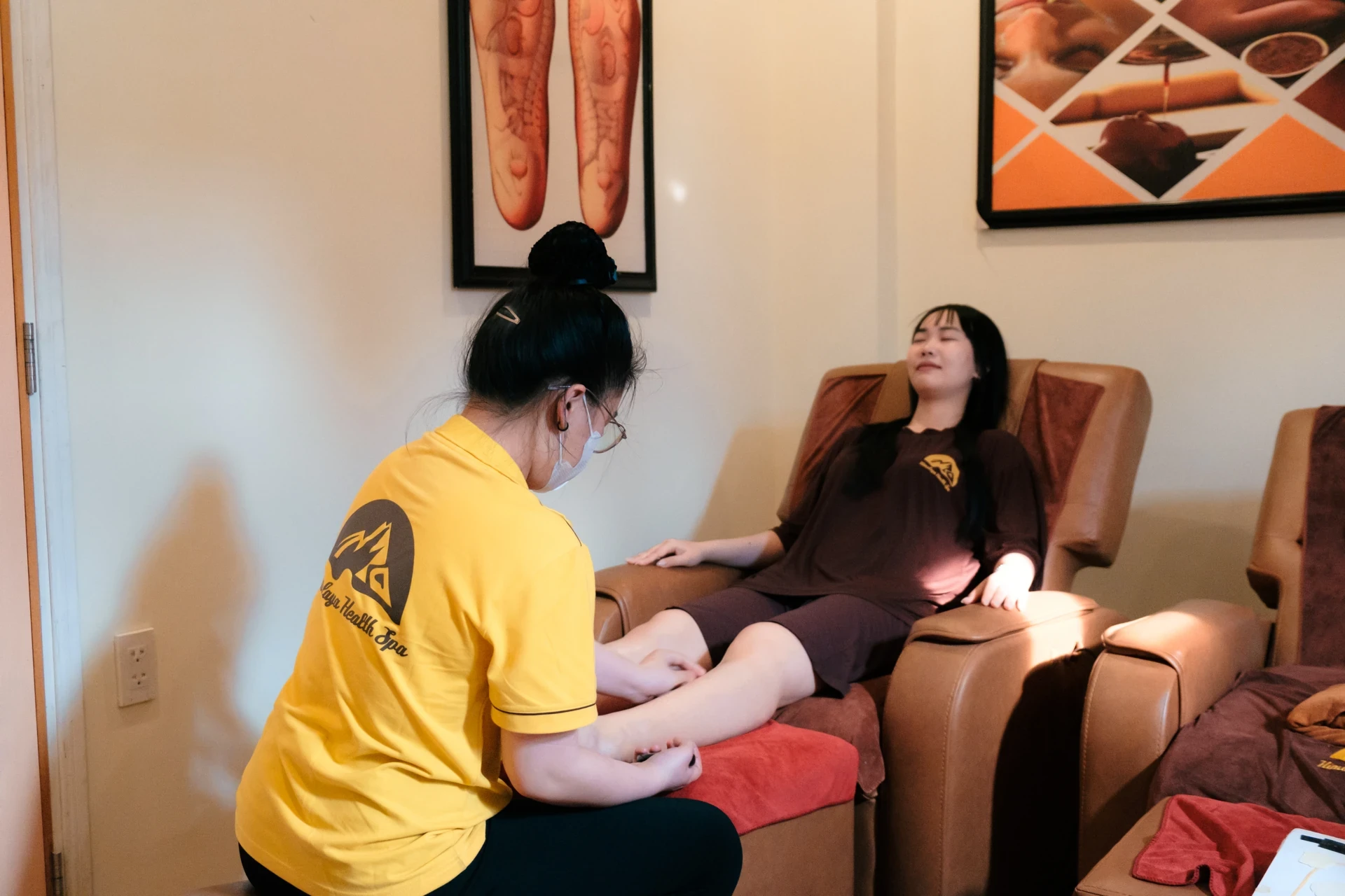Kỹ thuật viên Himalaya massage chân cho khách trên ghế thư giãn